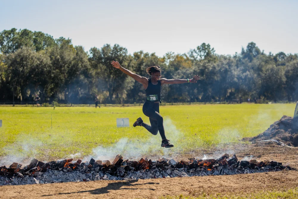 A racer leaps over the fire obstacle