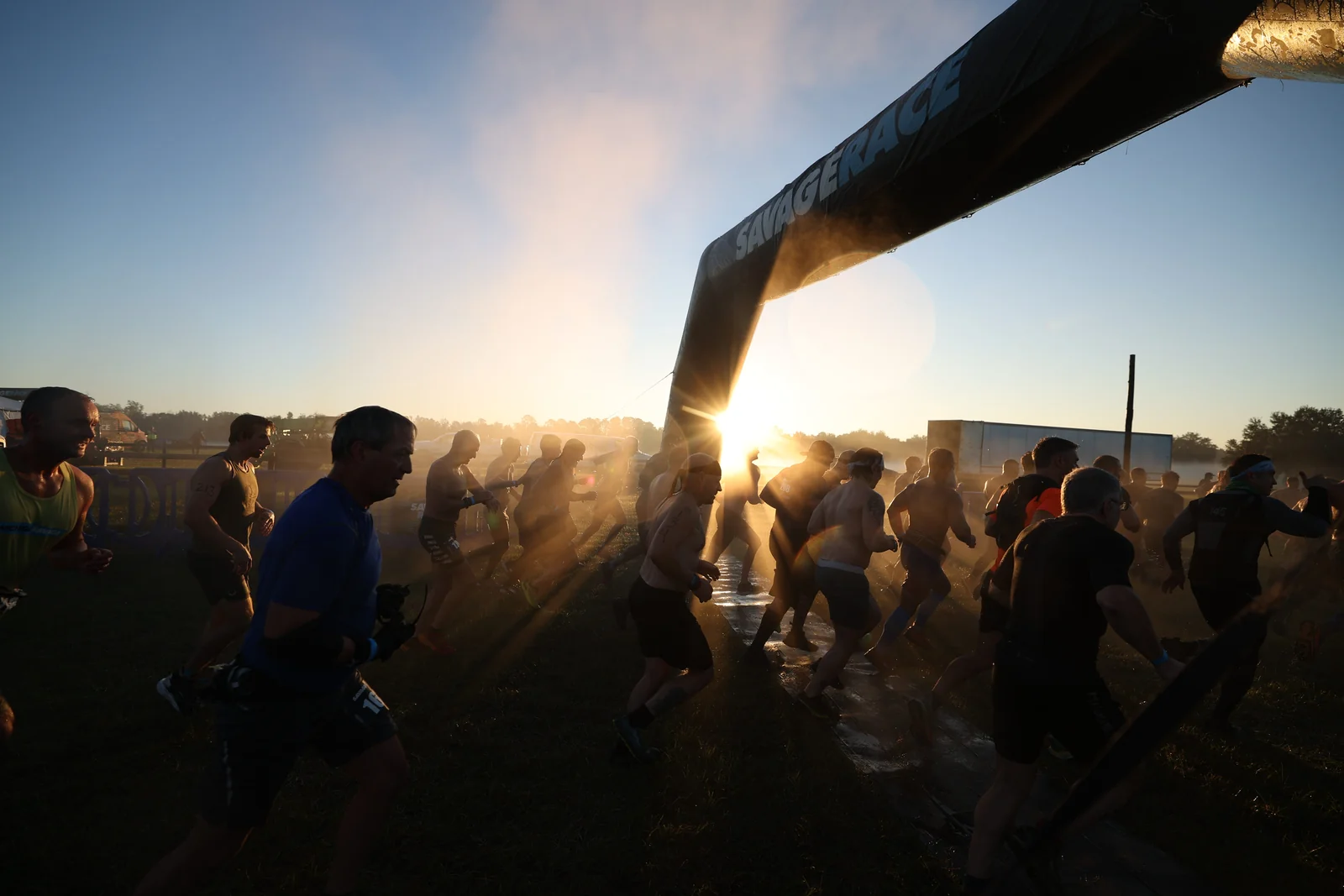 Racers gather beneath the starting arch in the early sunshine