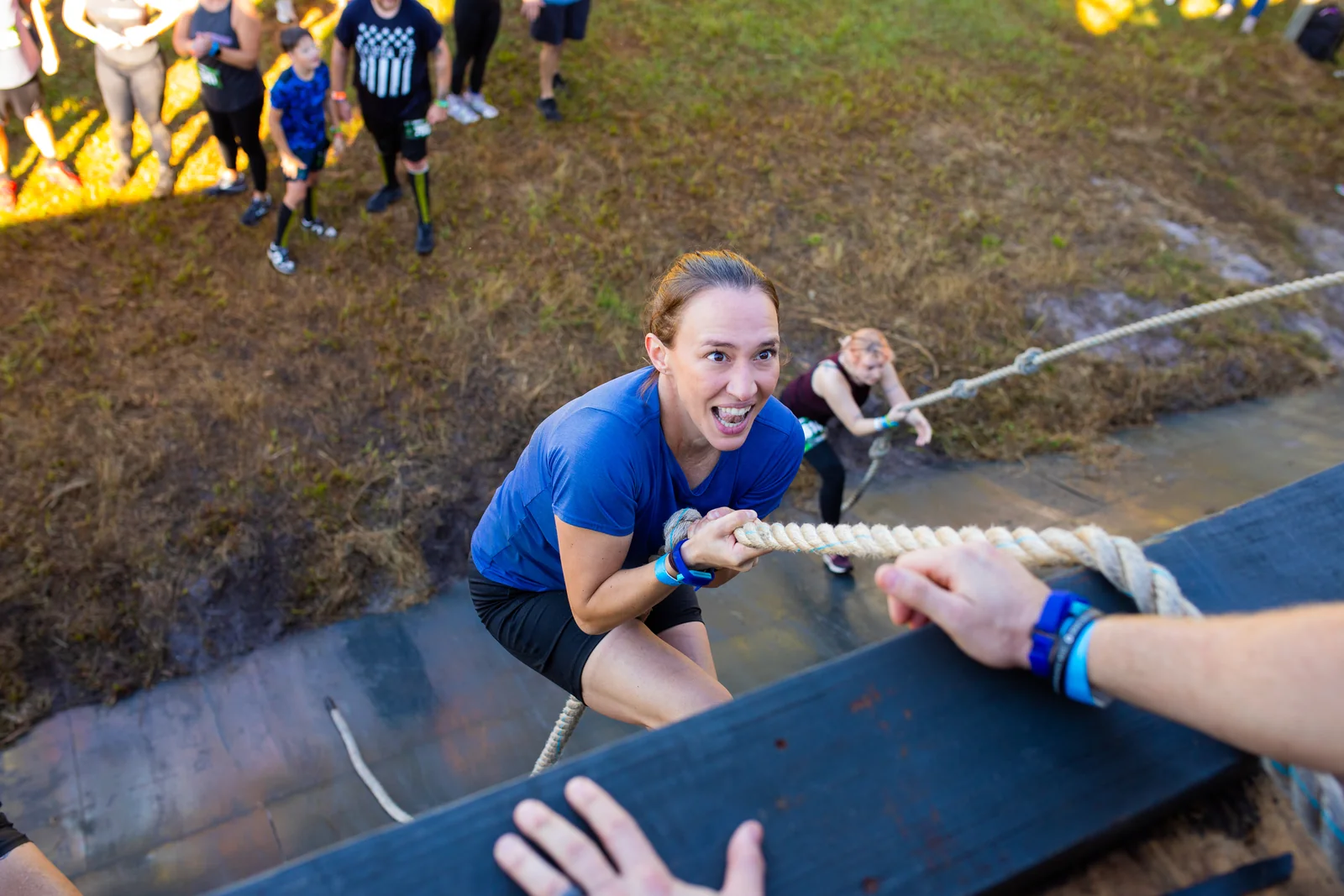 A teammate offers a hand to a racer climbing a steep ramp