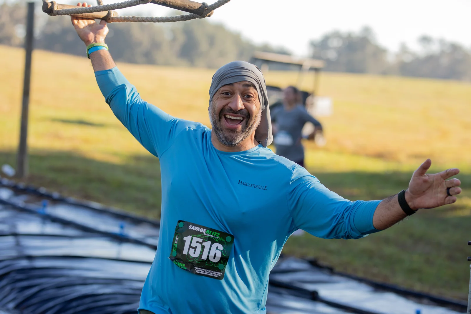 A smiling racer in blue celebrates with arms outstretched