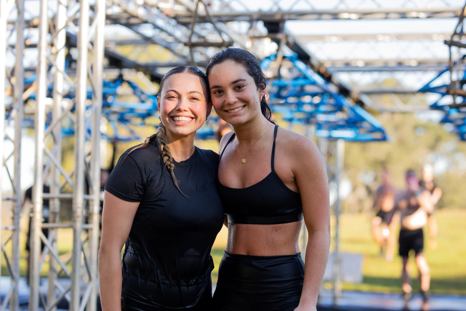 Two friends smile together beside an obstacle