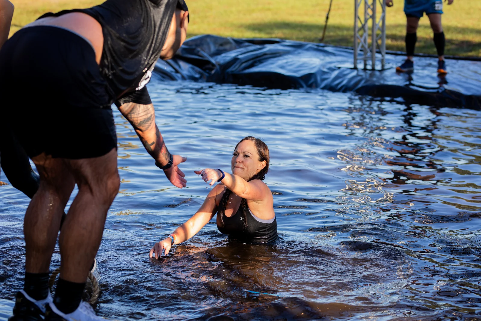 A racer reaches out to help another participant out of the water