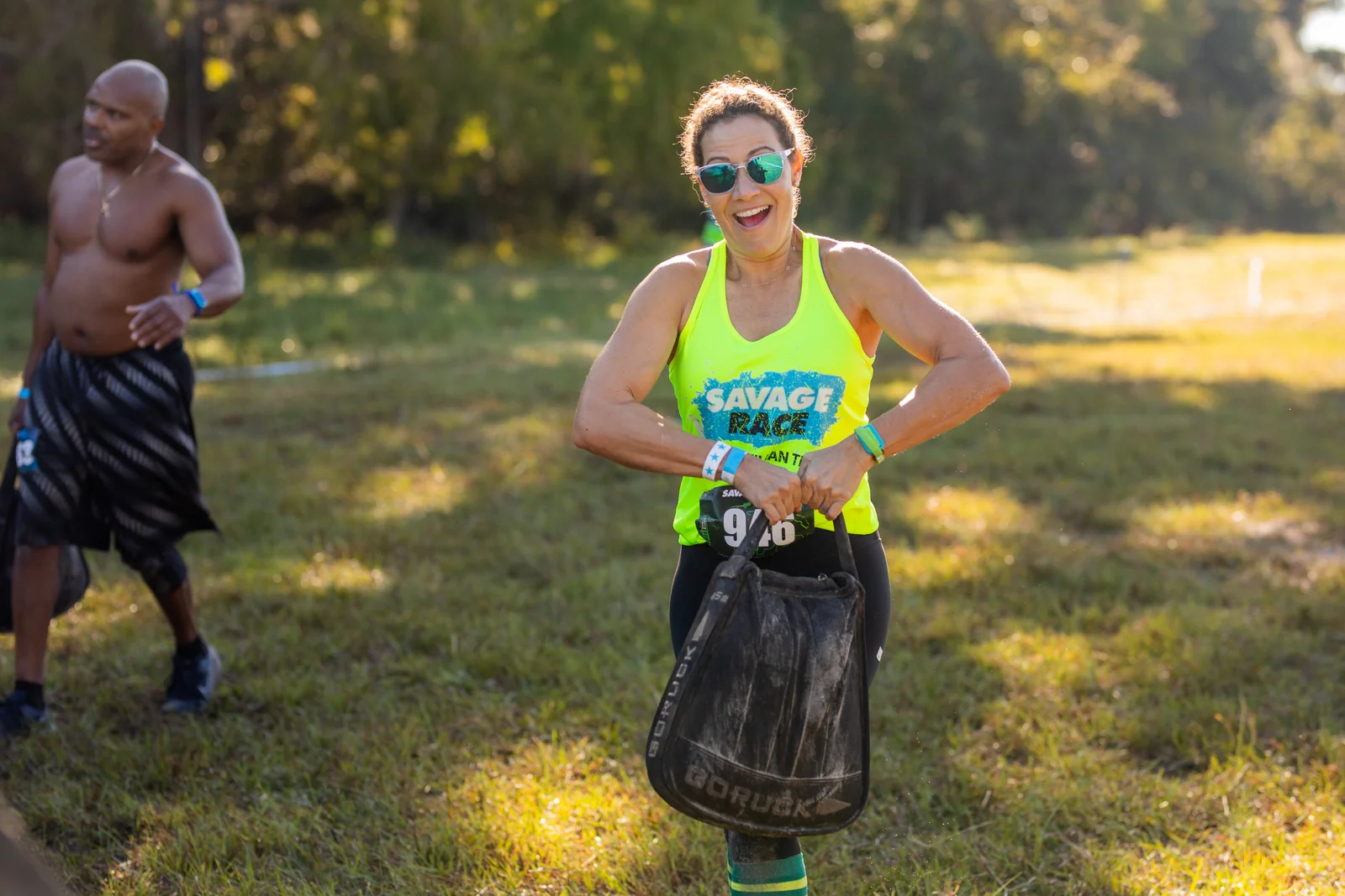 A smiling racer carries a weight along the course